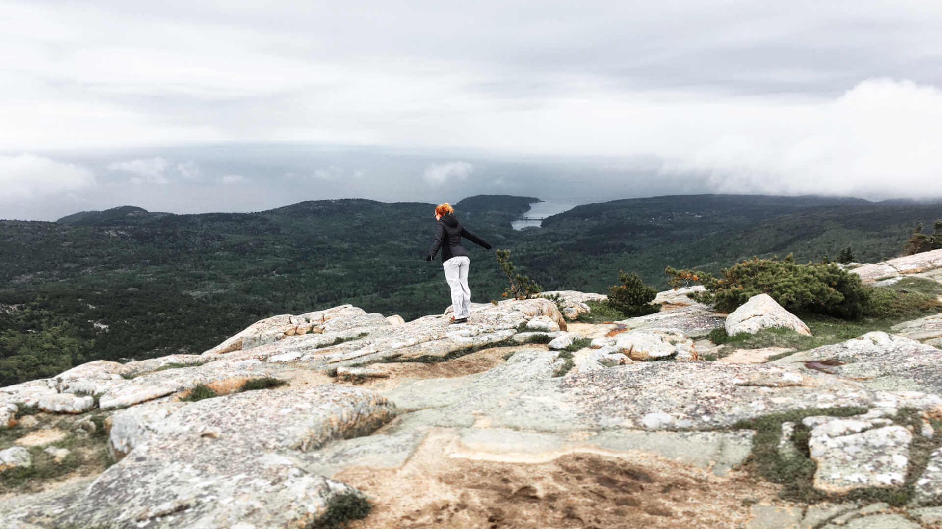 Jenni staring down over a peak in Acadia National Park, balancing near the edge - keeping things just right like with work-life balance.