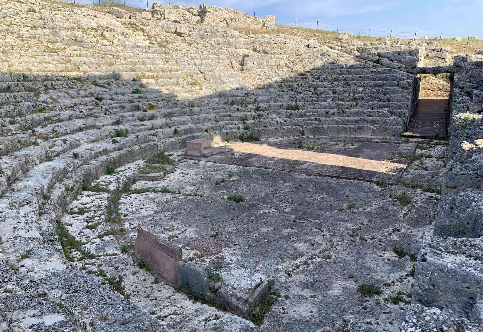 Acinipo's Roman amphitheater ruins under a stark sun.